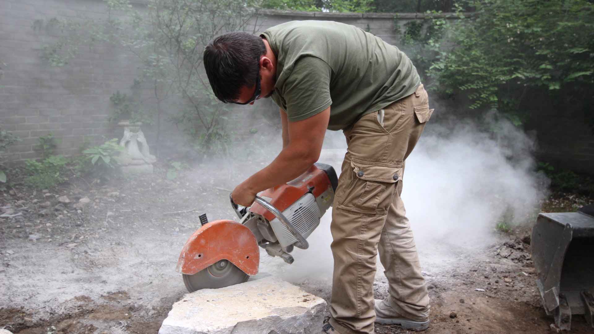 Landscape installation, construction and hardscaping: Nate of Old South Landscape Professionals cutting stone.